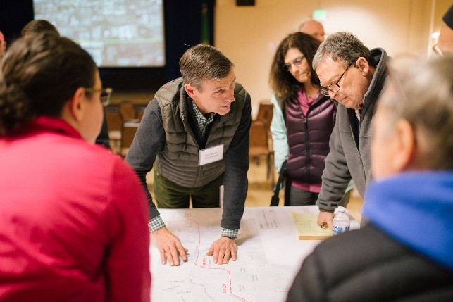 Photograph of a previous neighborhood forum, with community members looking at a project map with Sound Transit staff.